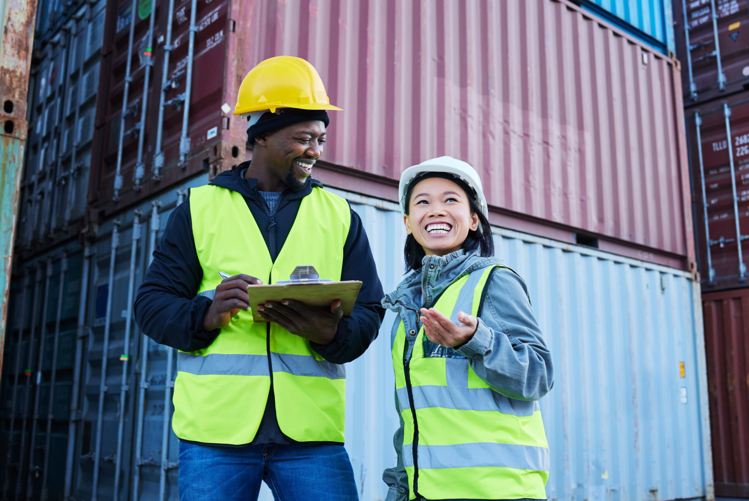 Warehouse, management and cargo stock with man and woman discuss checklist and laughing at factory .